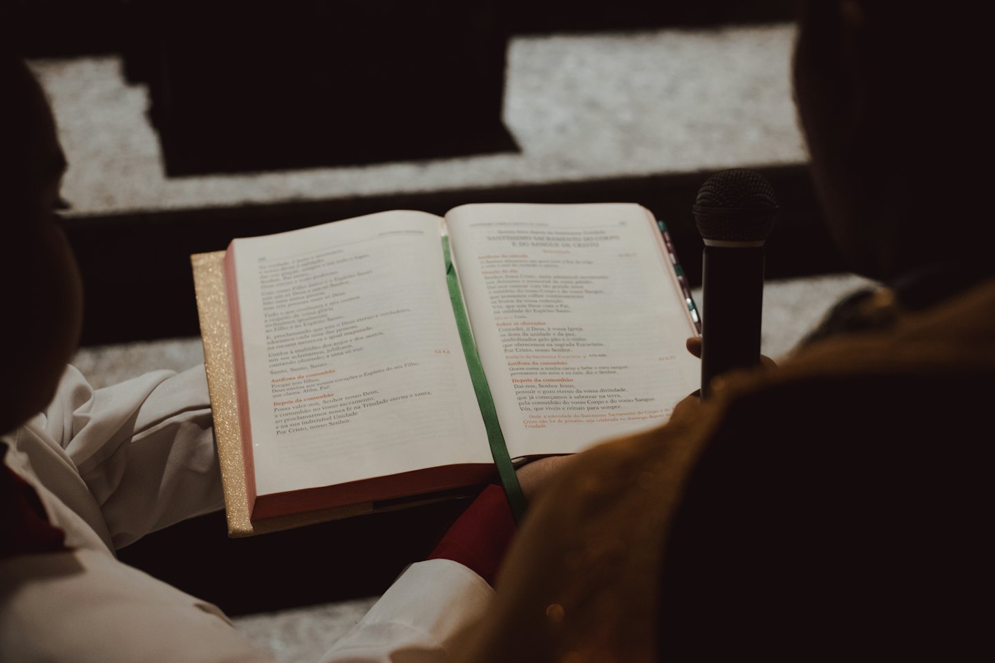 A religious leader reads from a book into a microphone.